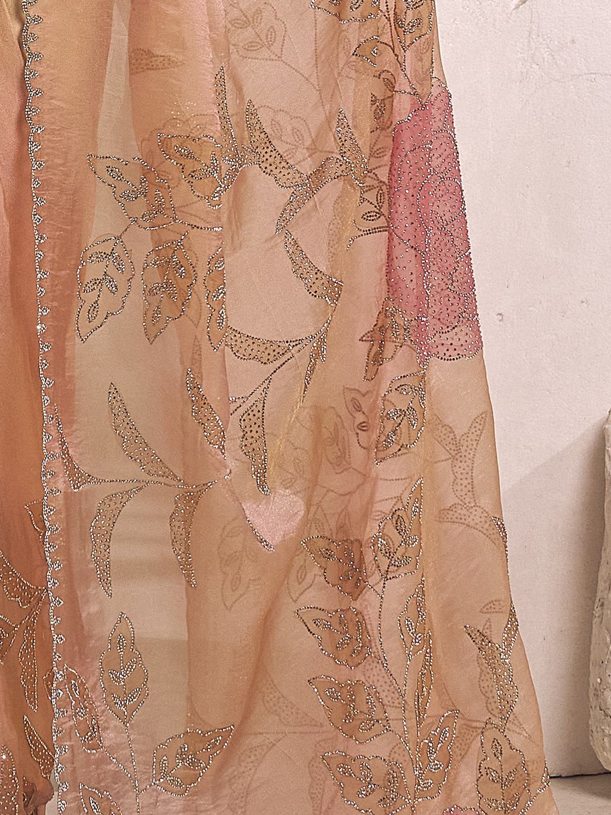 Pallu detail of peach organza saree showing ornamented surface design and scallop border