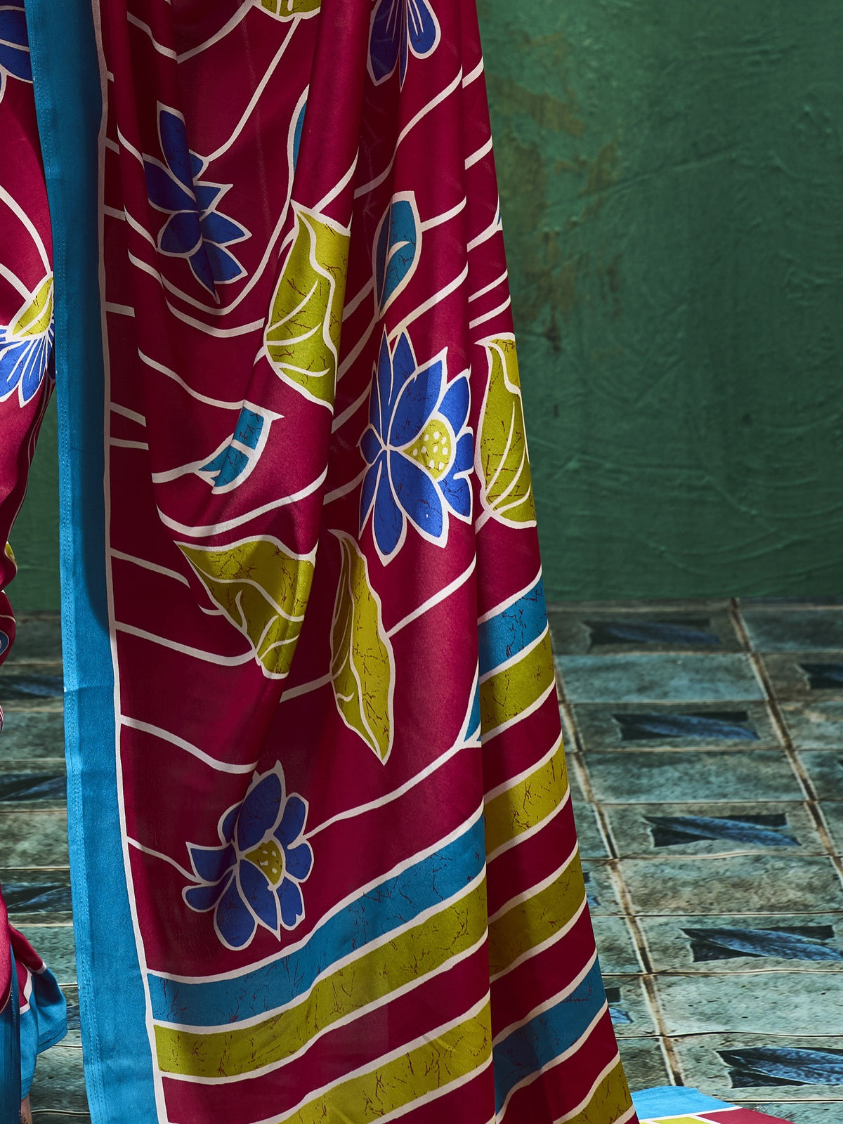 Pallu detail of maroon satin saree showing all-over floral design and printed border