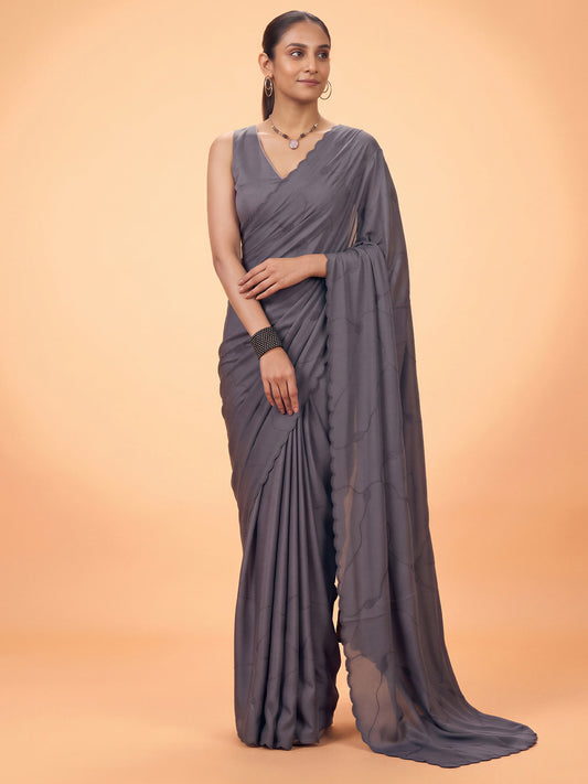 Woman wearing charcoal grey satin silk saree with ornamented surface design and charcoal grey blouse
