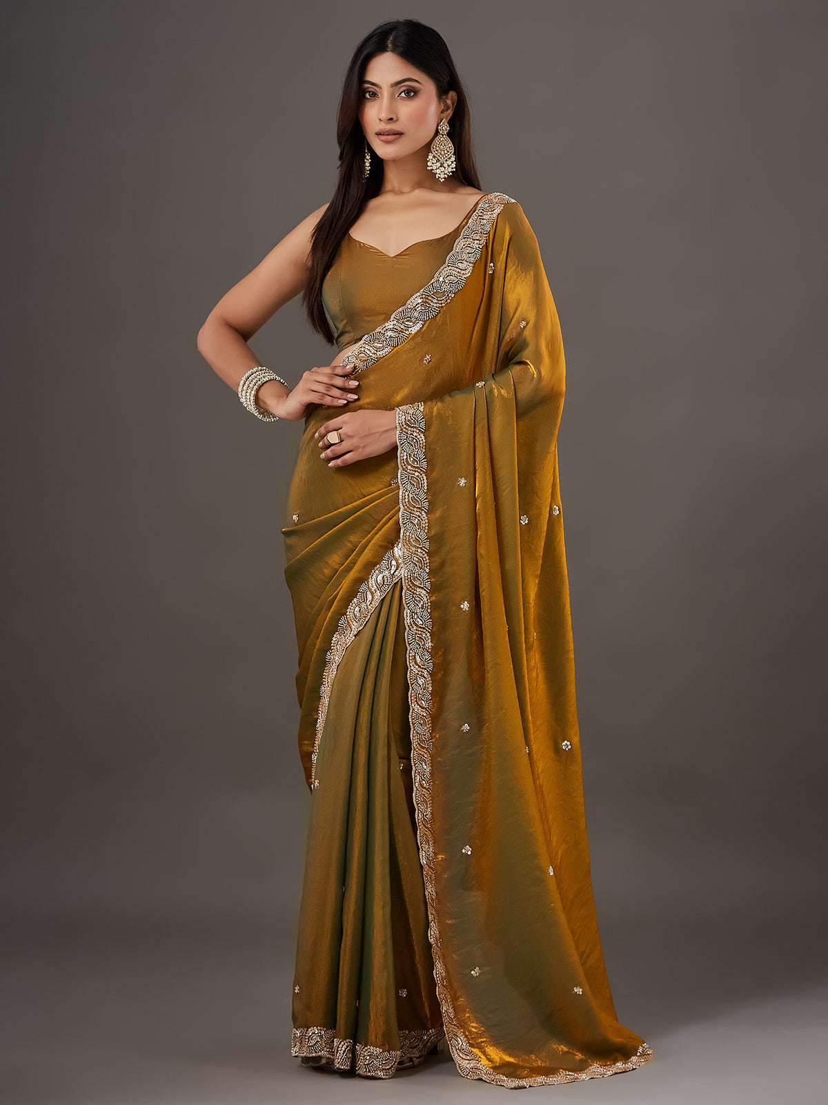 Woman wearing gold satin saree with ornamented surface design and gold blouse