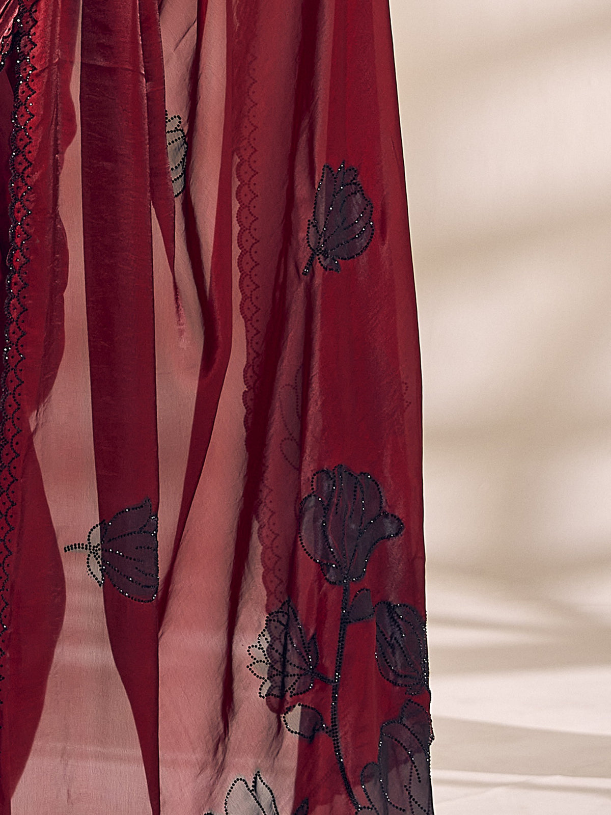 Pallu detail of maroon satin silk saree showing ornamented surface design and scallop border