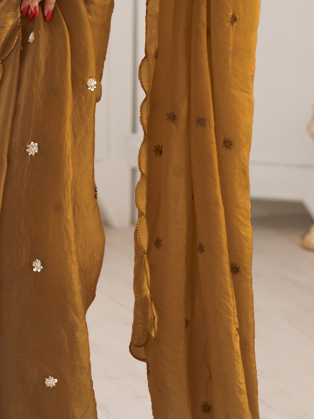 Pallu detail of gold satin saree showing ornamented surface design and embroidered border