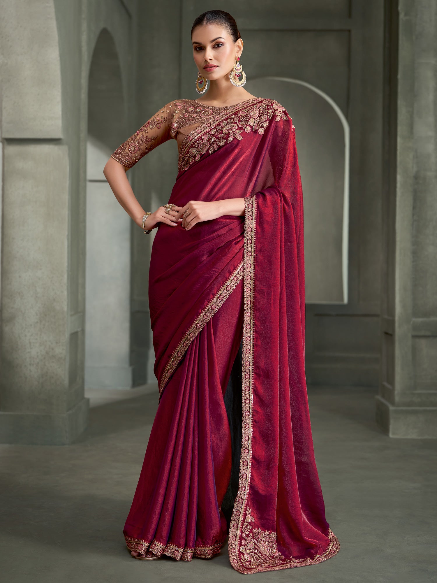 Woman wearing wine satin silk saree with embroidered motif work and nude blouse