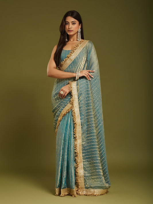 Woman wearing light blue satin saree with ornamented surface design and light blue blouse