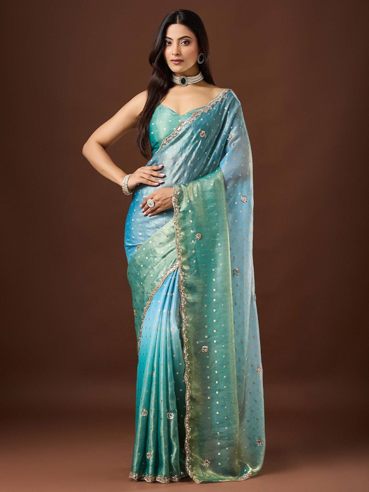 Woman wearing light blue satin saree with ornamented surface design and light blue blouse