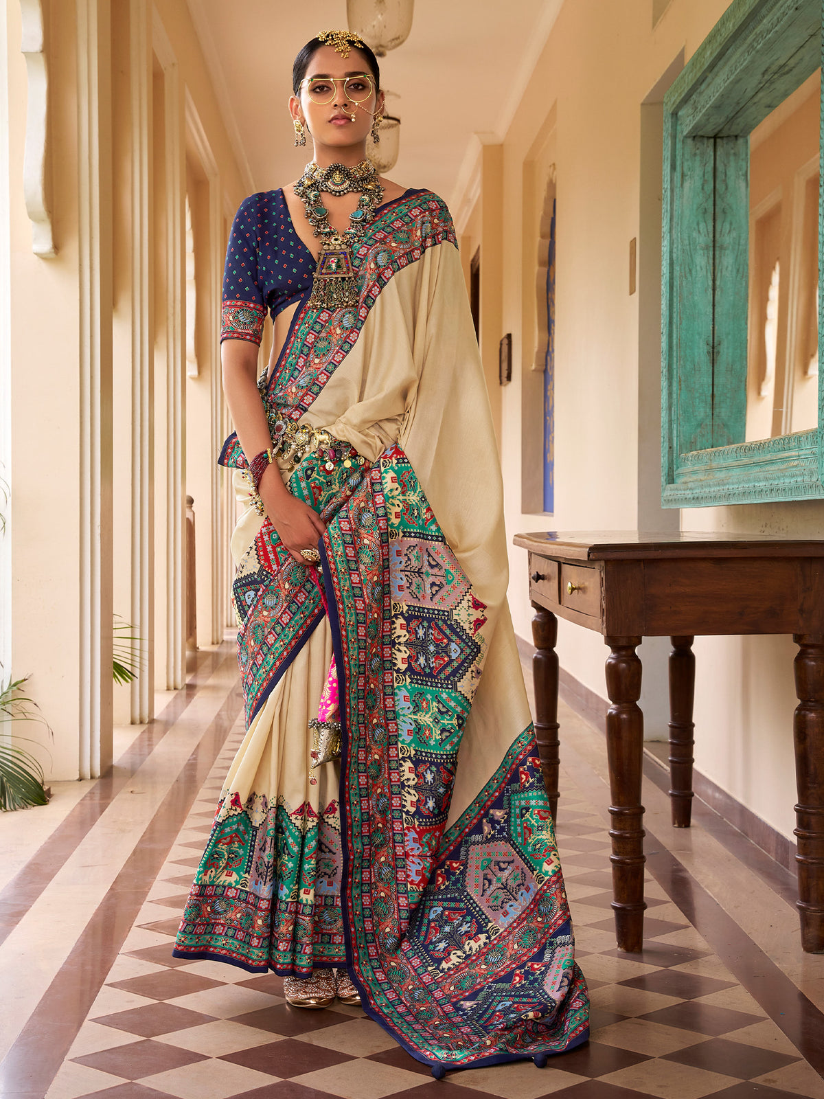 Woman wearing beige silk blend saree with traditional indian motif work and navy blue blouse
