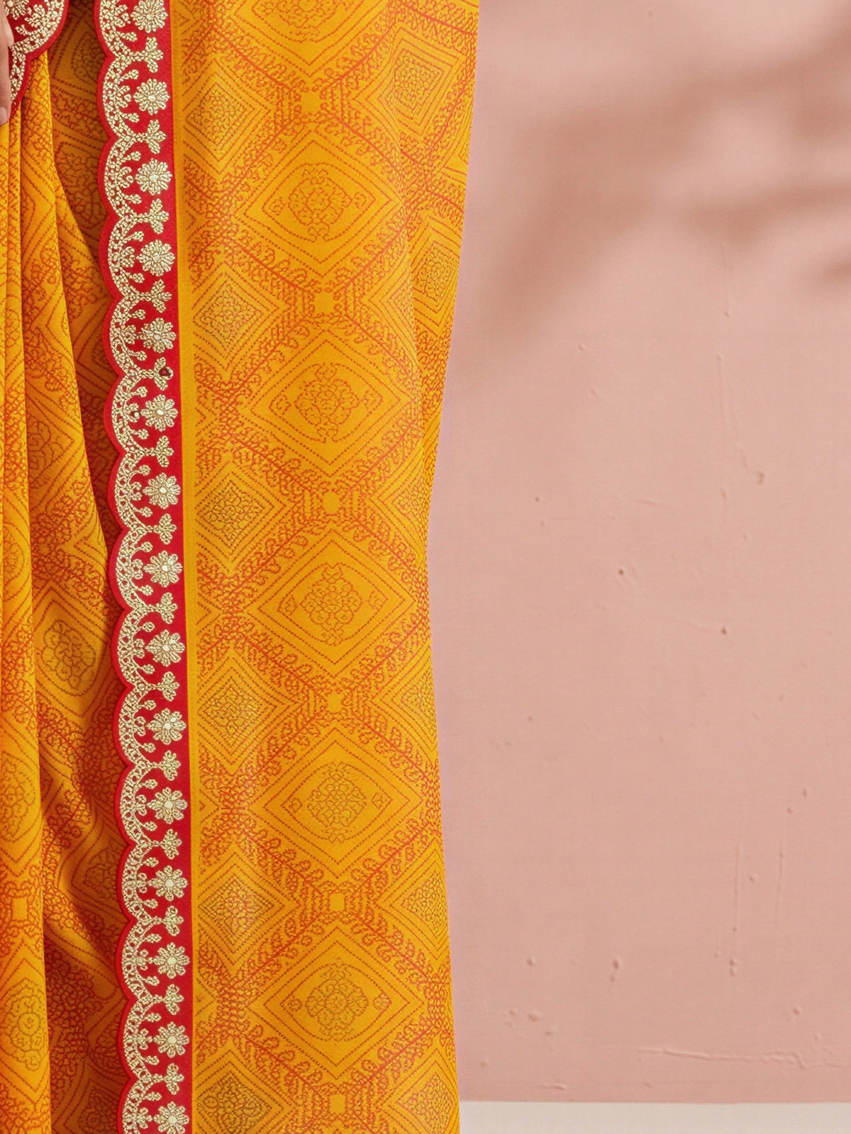 Pallu detail of mustard georgette saree showing bandhani tie-dye dot work and embellished border