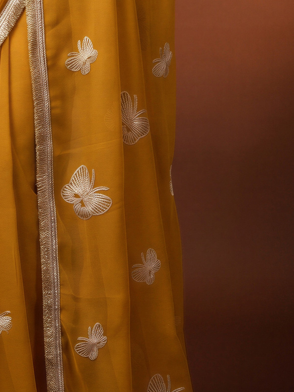 Pallu detail of yellow georgette saree showing embroidered motif work and embellished border