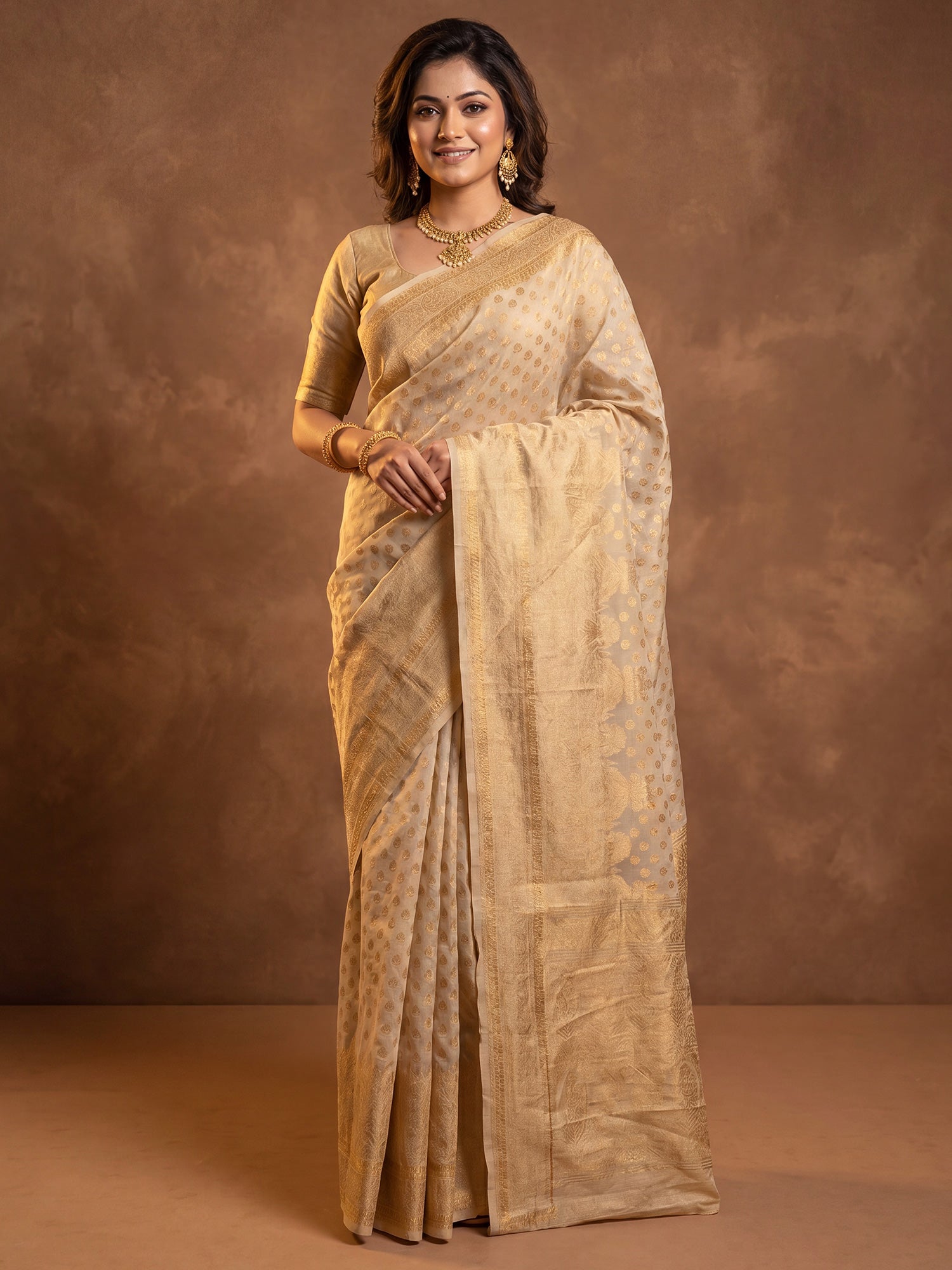Woman wearing cream silk blend saree with zari butta (metallic motif) work and cream blouse