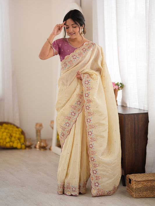 Woman wearing off white satin saree with ornamented surface design and lavender blouse