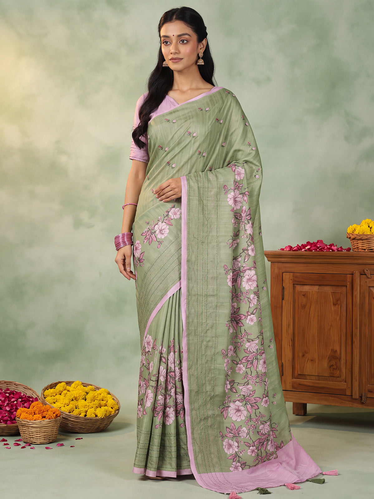 Woman wearing light green silk blend saree with all-over floral design and pink blouse