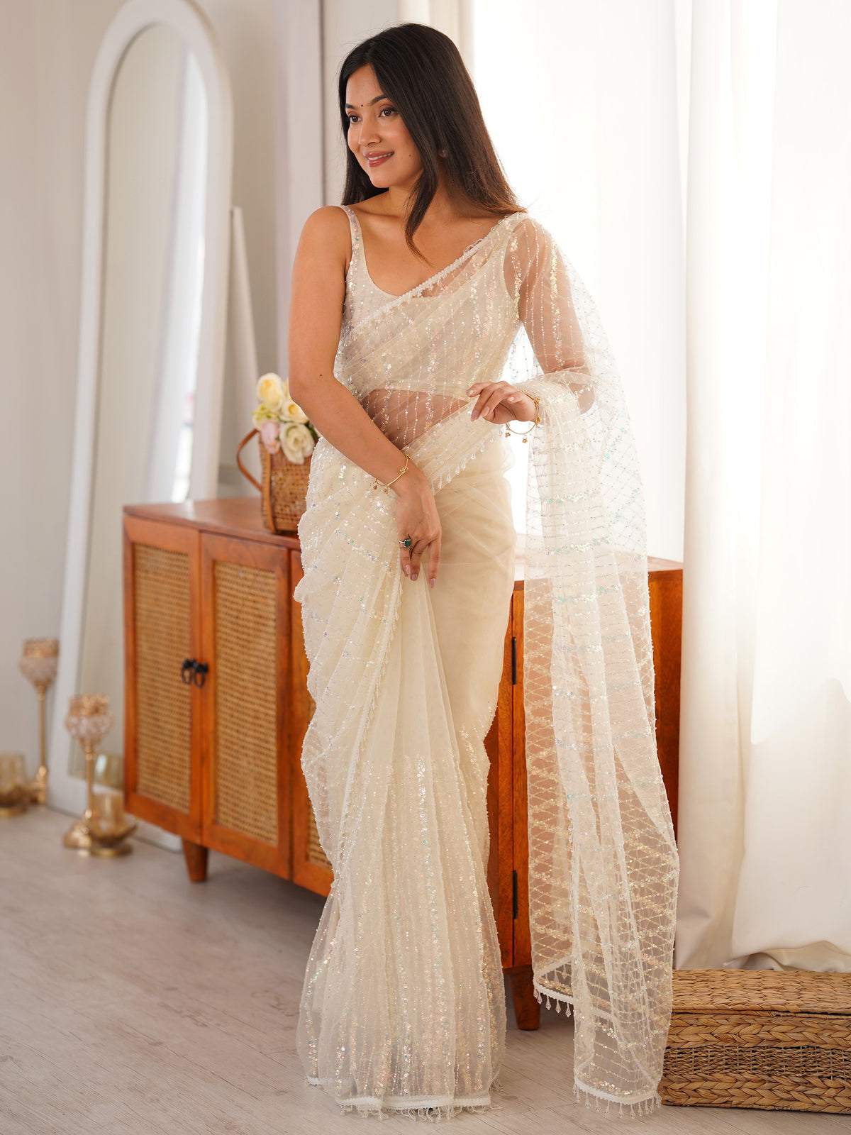 Woman wearing off white net saree with ornamented surface design and off white blouse