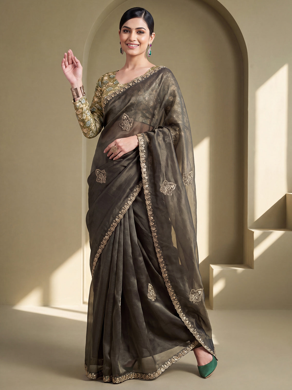 Woman wearing olive tissue saree with ornamented surface design and light green blouse