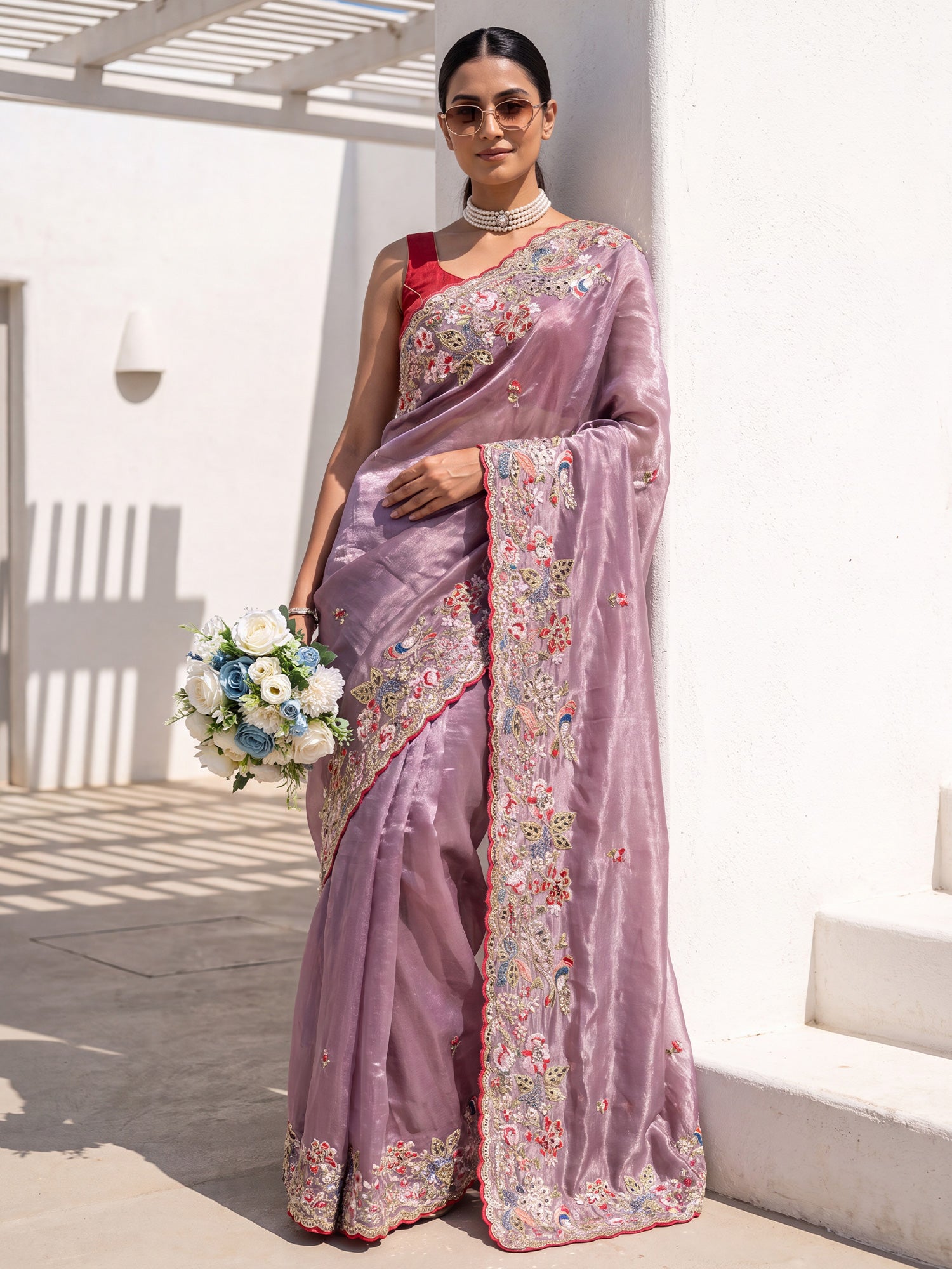 Woman wearing purple organza saree with embroidered motif work and red blouse