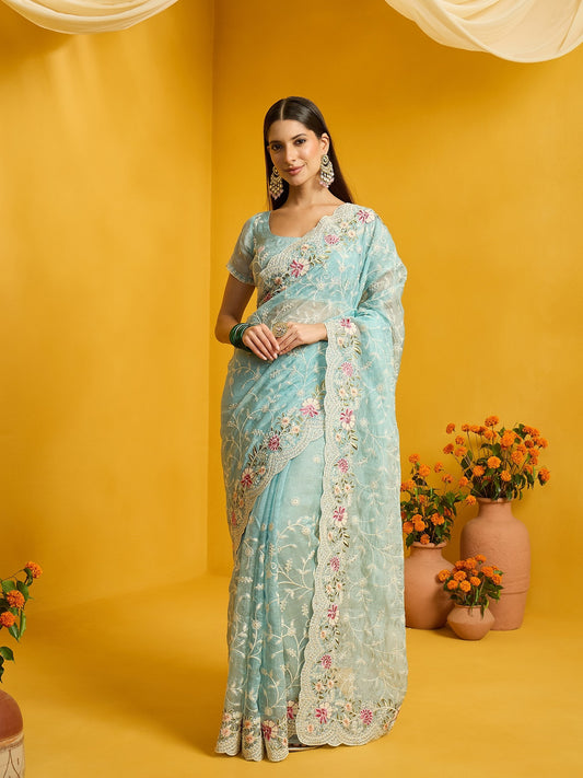 Woman wearing light blue organza saree with ornamented surface design and light blue blouse