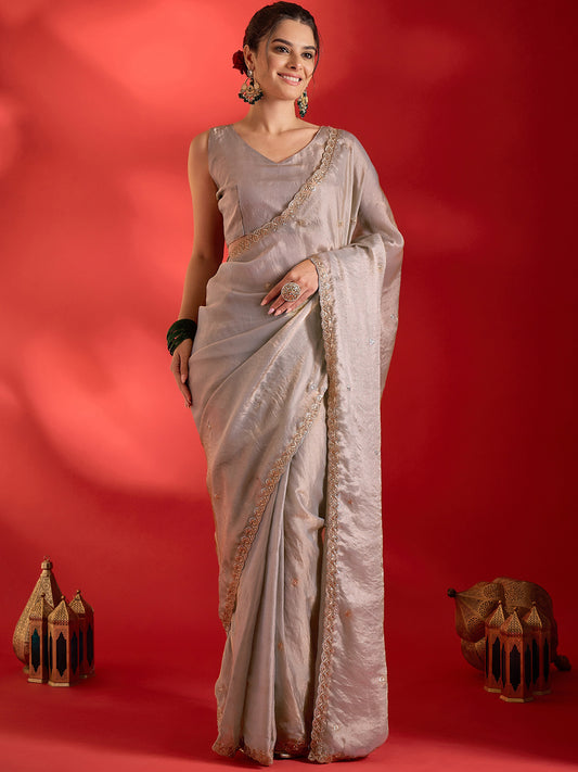 Woman wearing beige paper silk saree with ornamented surface design and beige blouse