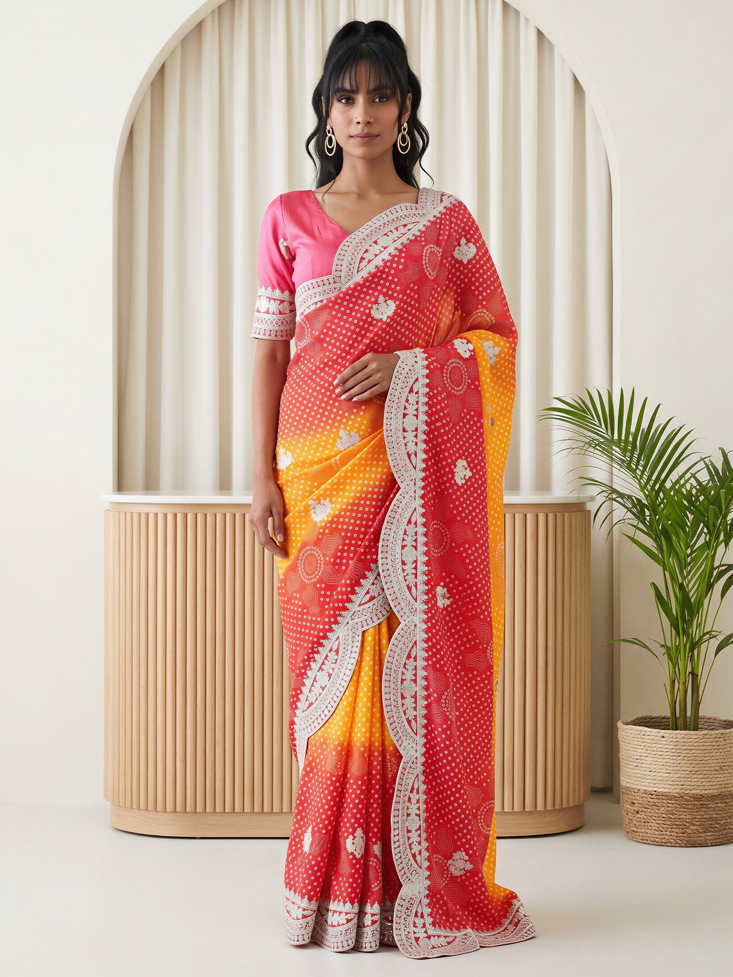 Woman wearing red chinnon saree with bandhani tie-dye dot work and pink blouse