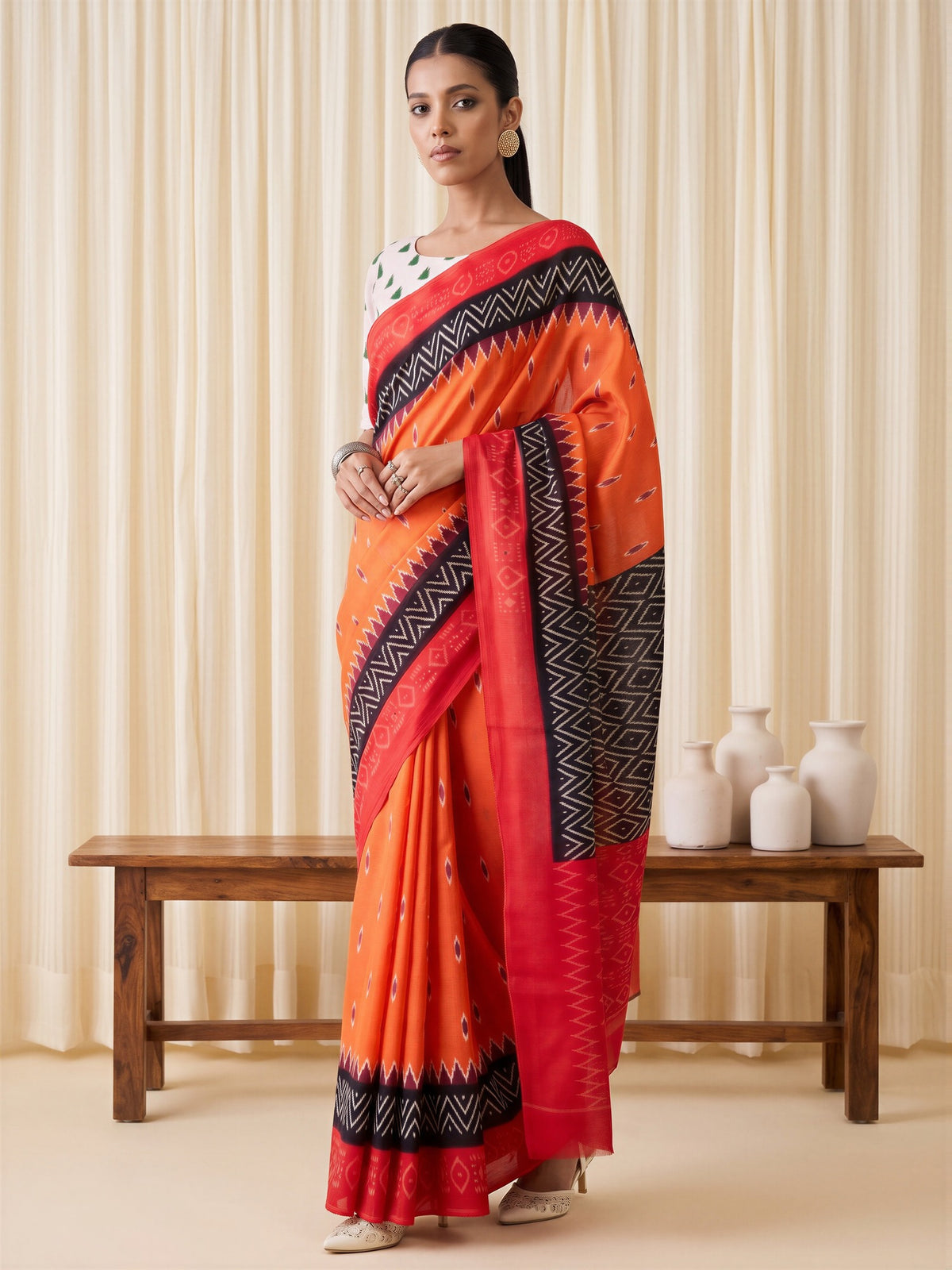 Woman wearing orange cotton blend saree with ikat resist-dyed pattern and black blouse