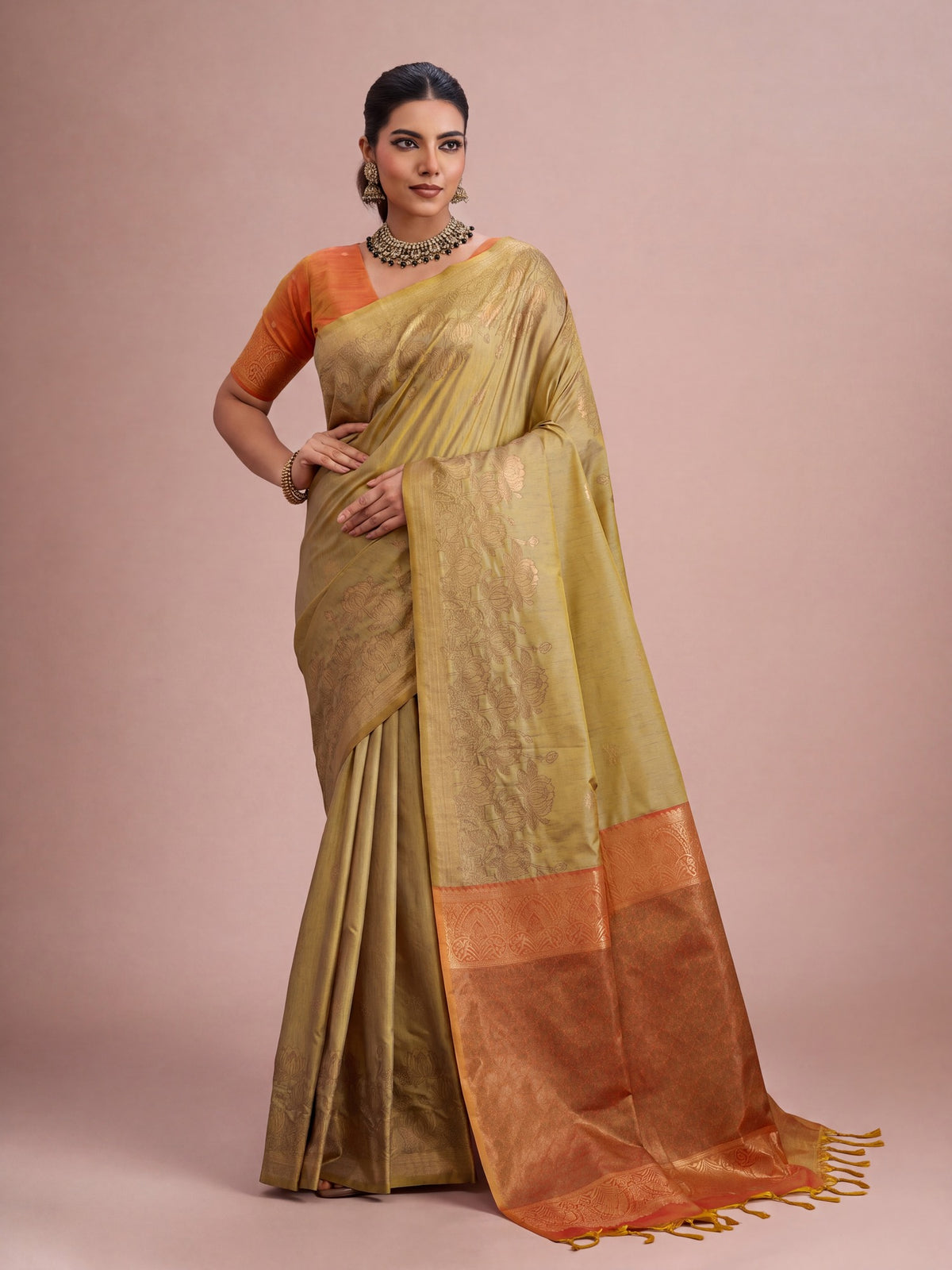 Woman wearing mustard tussar silk saree with traditional indian motif work and orange blouse