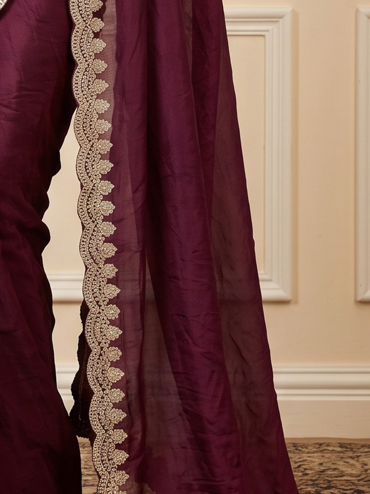 Pallu detail of burgundy tissue saree showing ornamented surface design and zari border