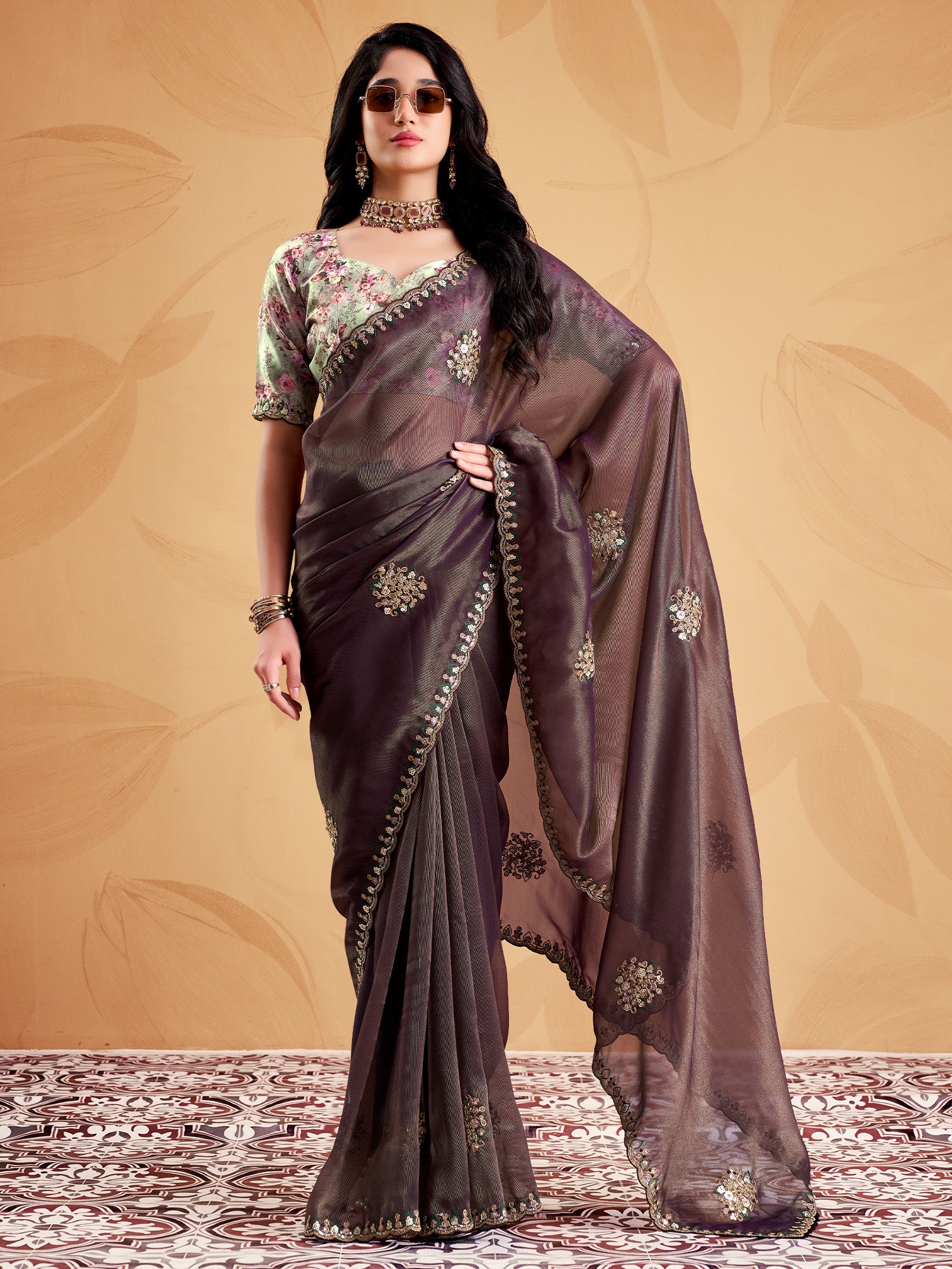 Woman wearing wine tissue saree with ornamented surface design and multicolored blouse