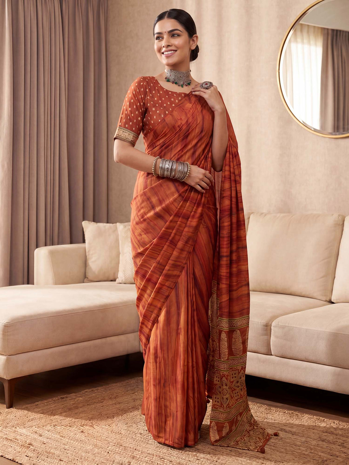 Woman wearing rust crepe saree with traditional indian motif work and rust blouse