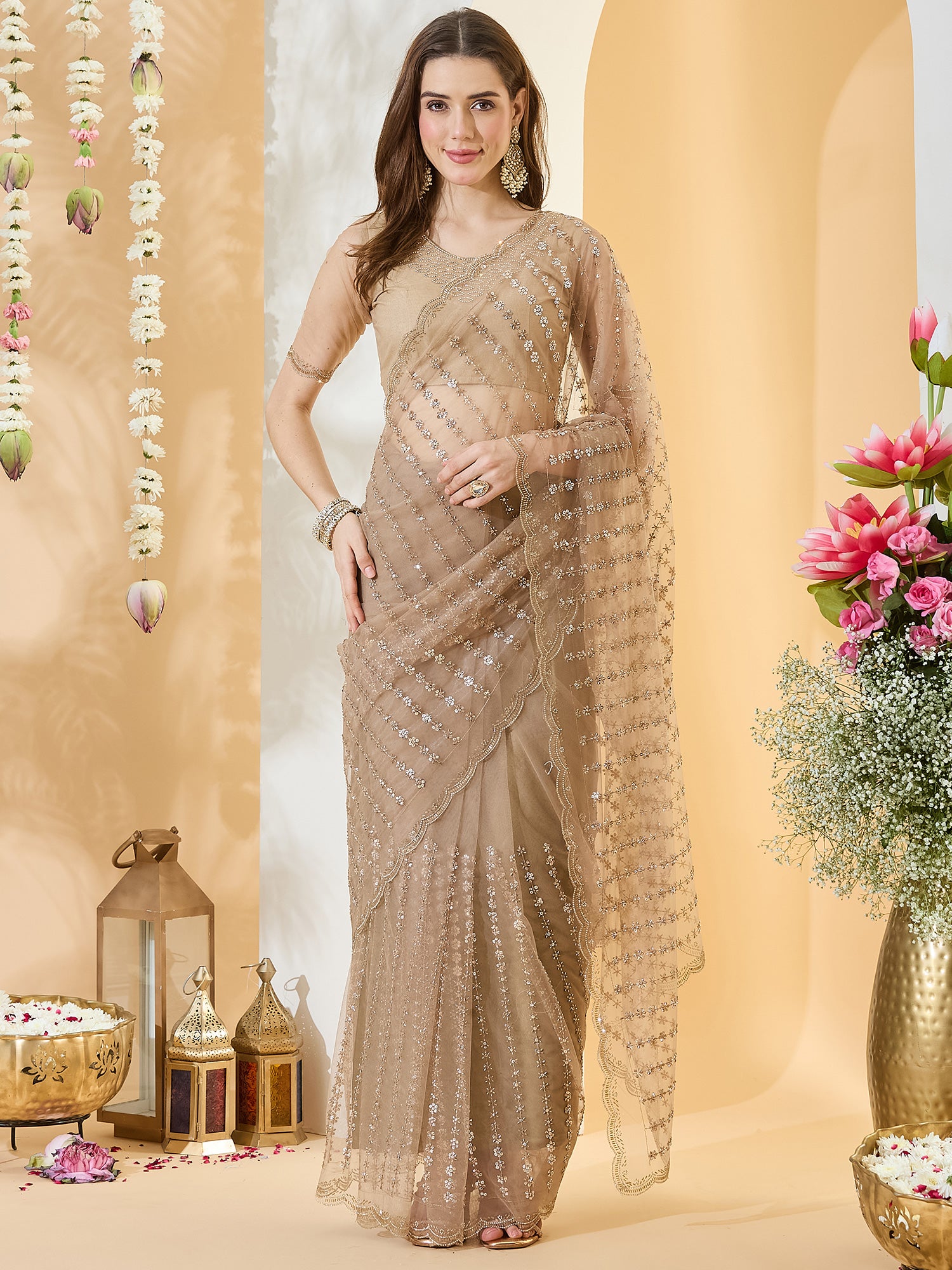 Woman wearing beige net saree with ornamented surface design and beige blouse