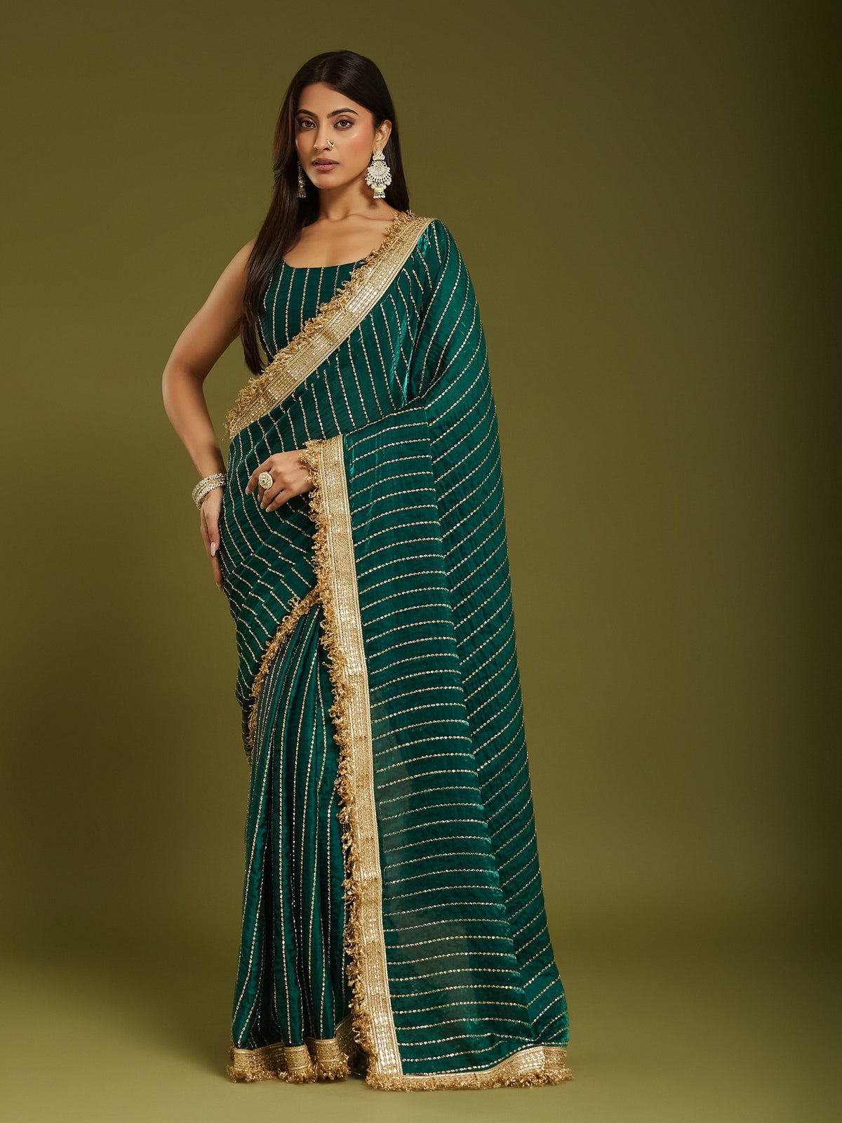 Woman wearing teal green satin saree with ornamented surface design and teal green blouse