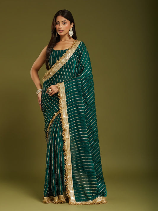 Woman wearing teal green satin saree with ornamented surface design and teal green blouse