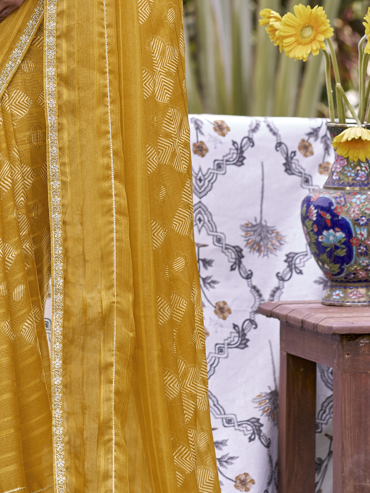 Pallu detail of mustard chiffon saree showing traditional indian motif work and embellished border