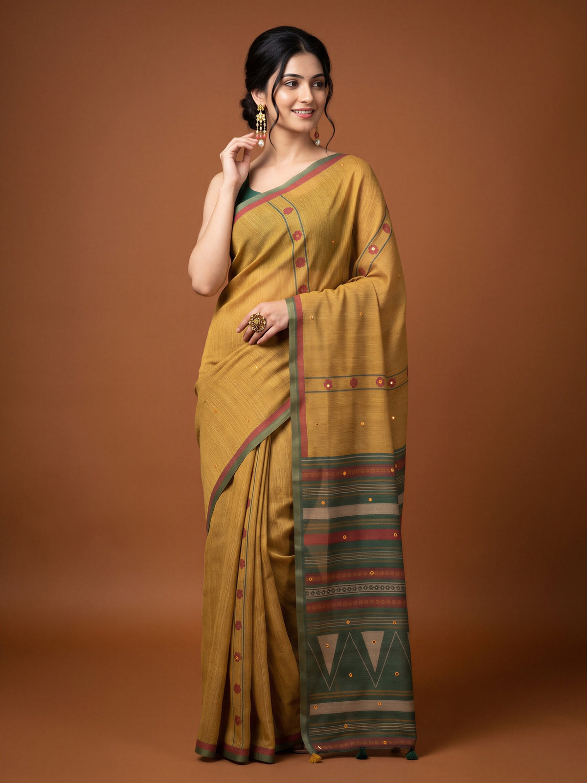 Woman wearing mustard linen blend saree with traditional indian motif work and green blouse