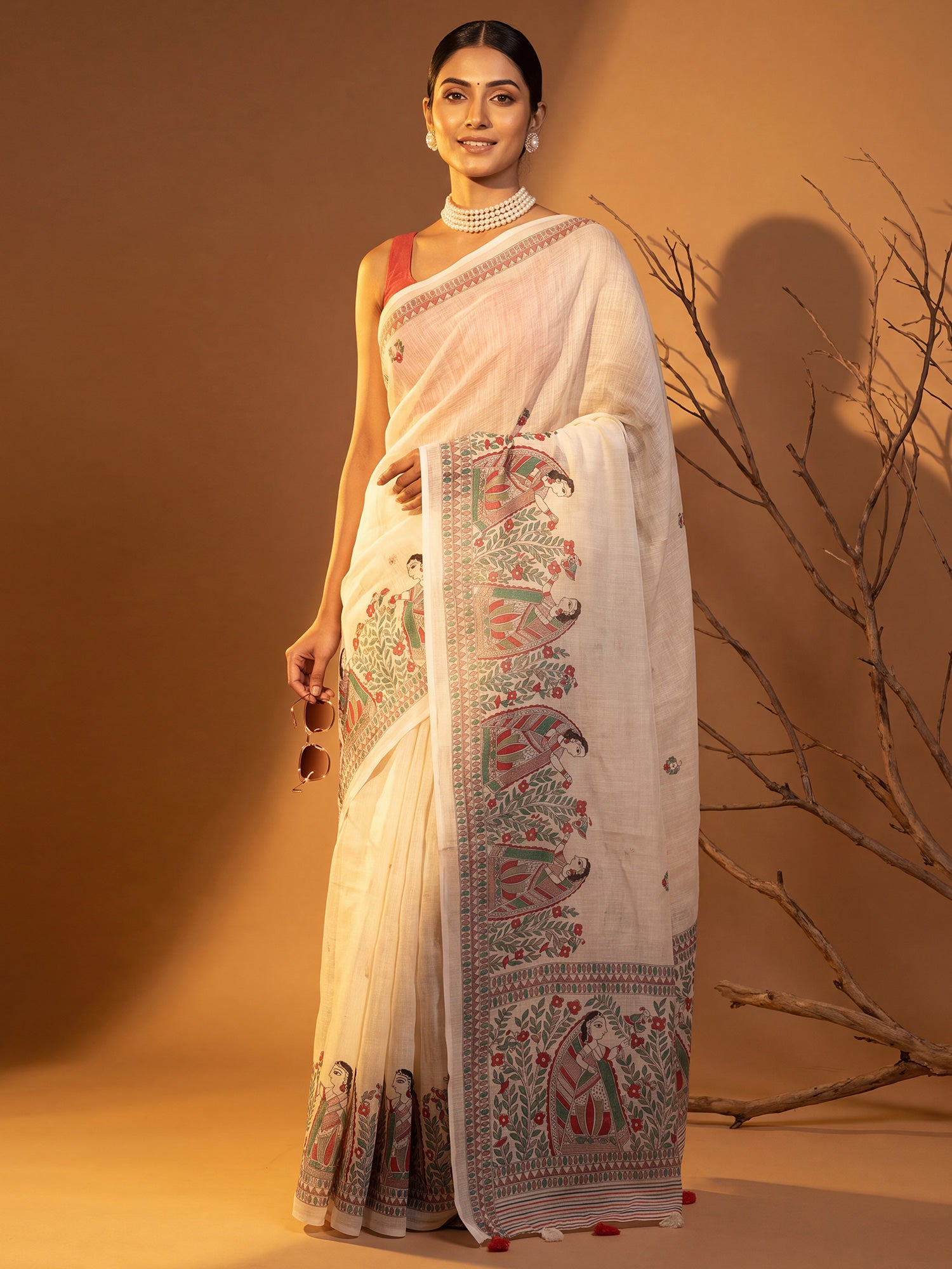 Woman wearing off white cotton linen saree with madhubani folk-art motifs and rust blouse