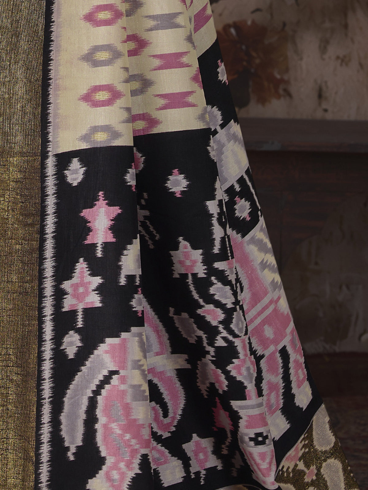 Pallu detail of off white silk blend saree showing ikat resist-dyed pattern and embellished border
