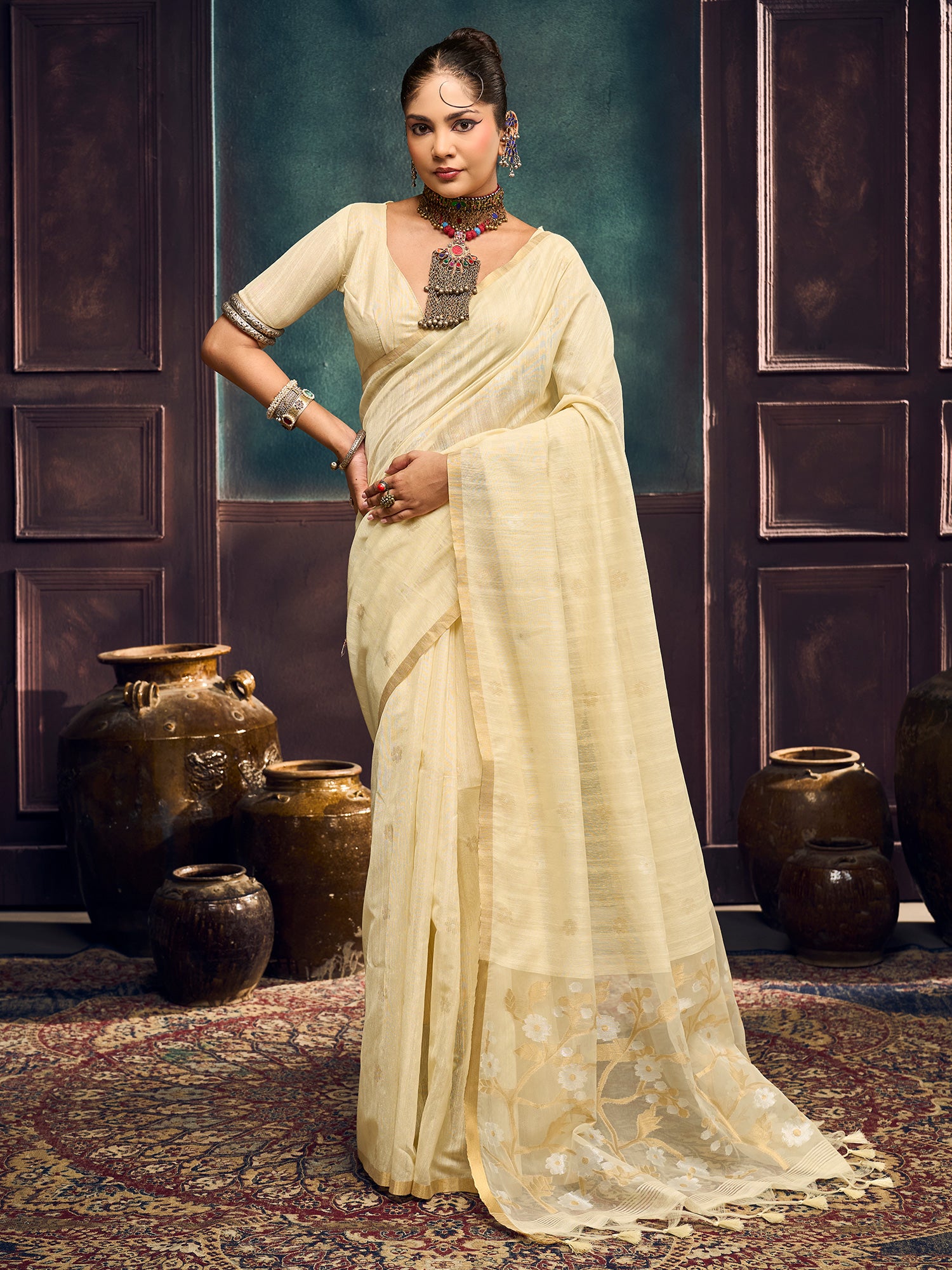 Woman wearing cream muga cotton saree with zari butta (metallic motif) work and cream blouse