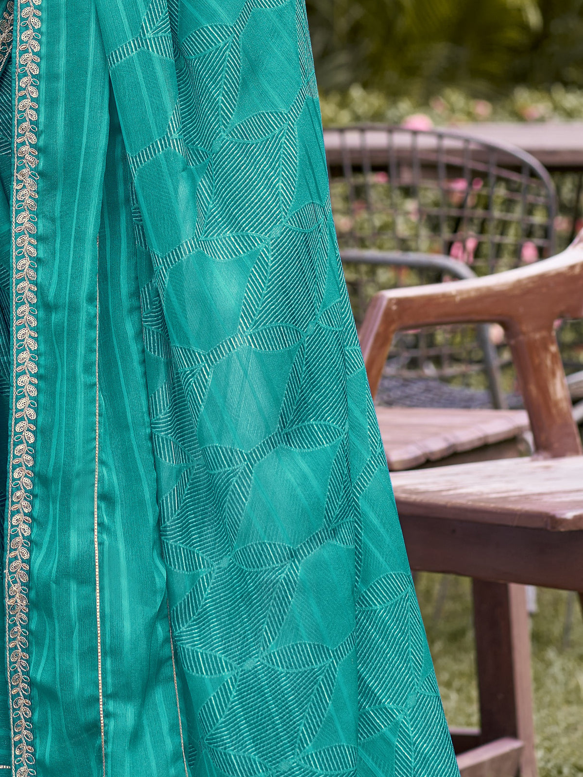 Pallu detail of turquoise blue chiffon saree showing traditional indian motif work and embellished border