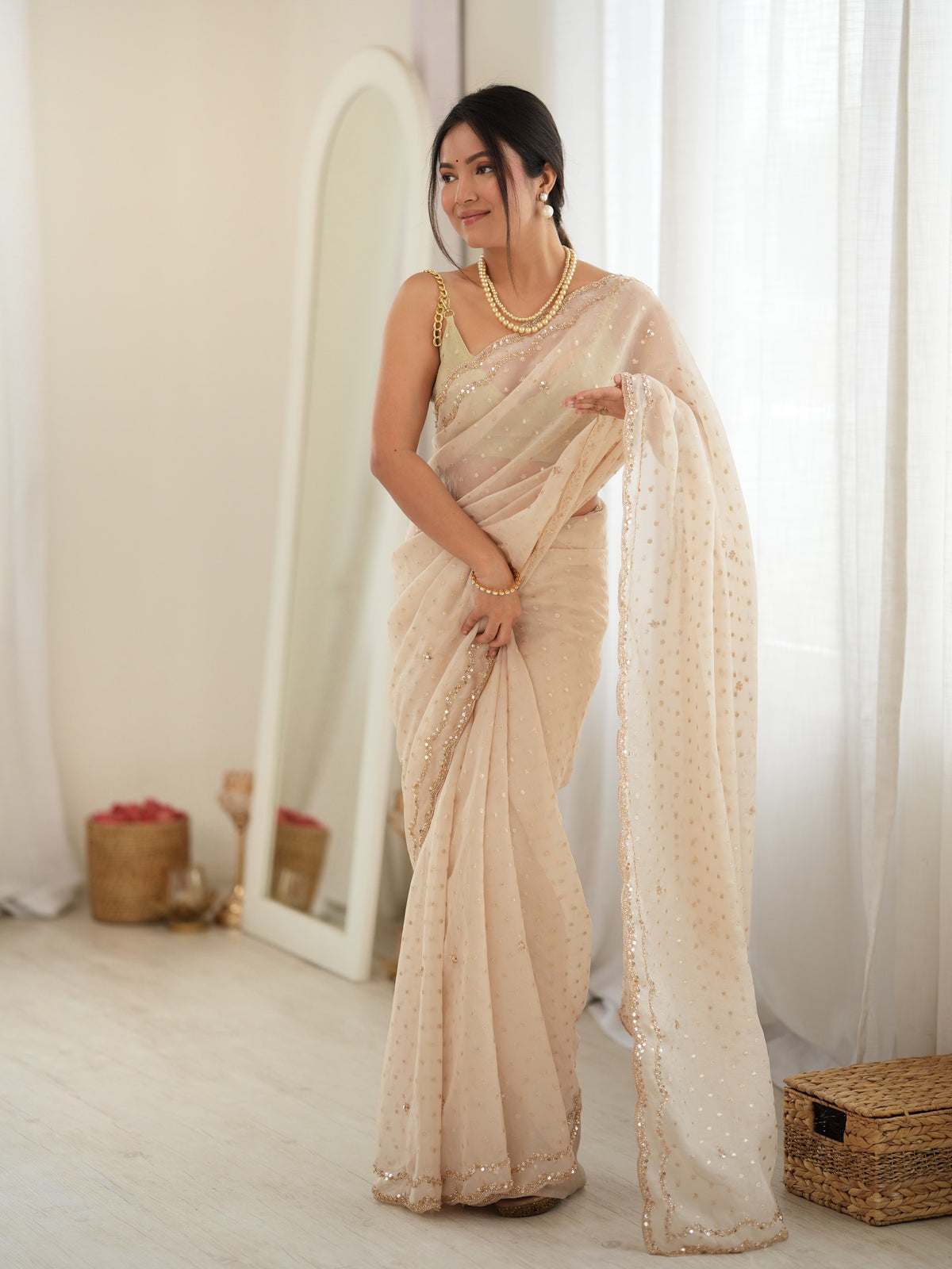 Woman wearing cream georgette saree with zari butta (metallic motif) work and cream blouse