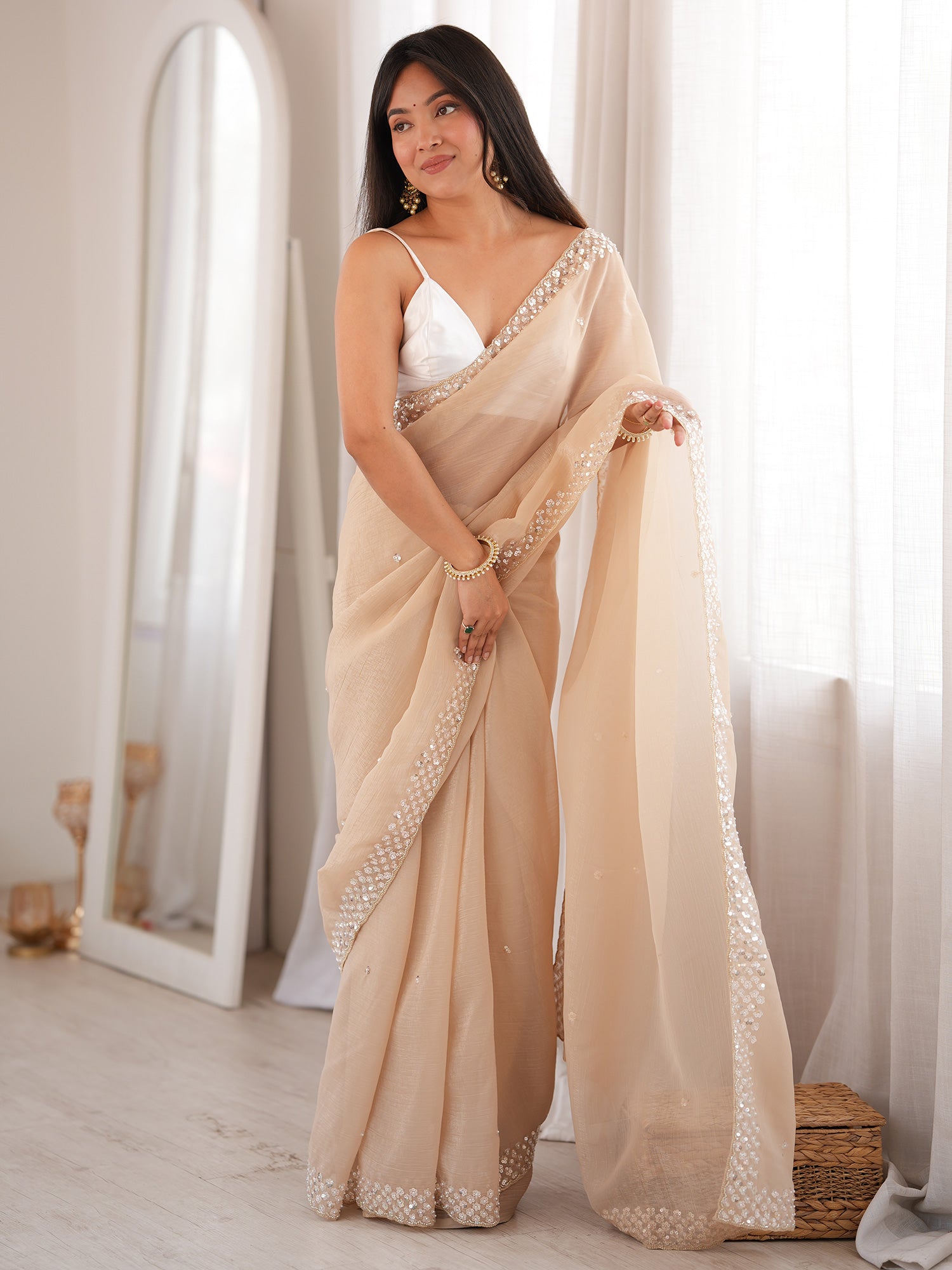 Woman wearing beige georgette saree with embroidered motif work and white blouse