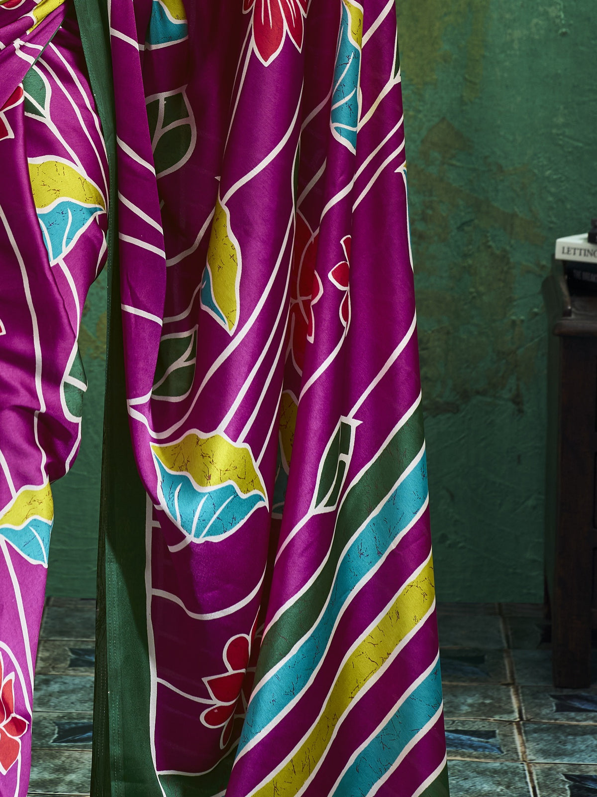 Pallu detail of magenta satin saree showing all-over floral design and printed border