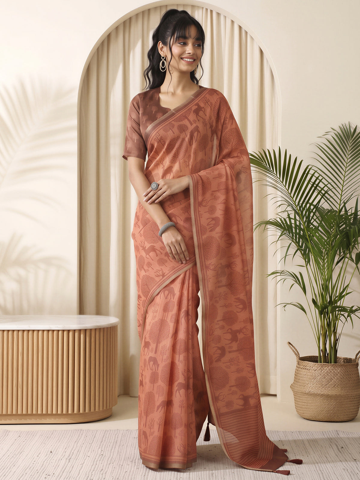 Woman wearing rust cotton linen saree with traditional indian motif work and light brown blouse