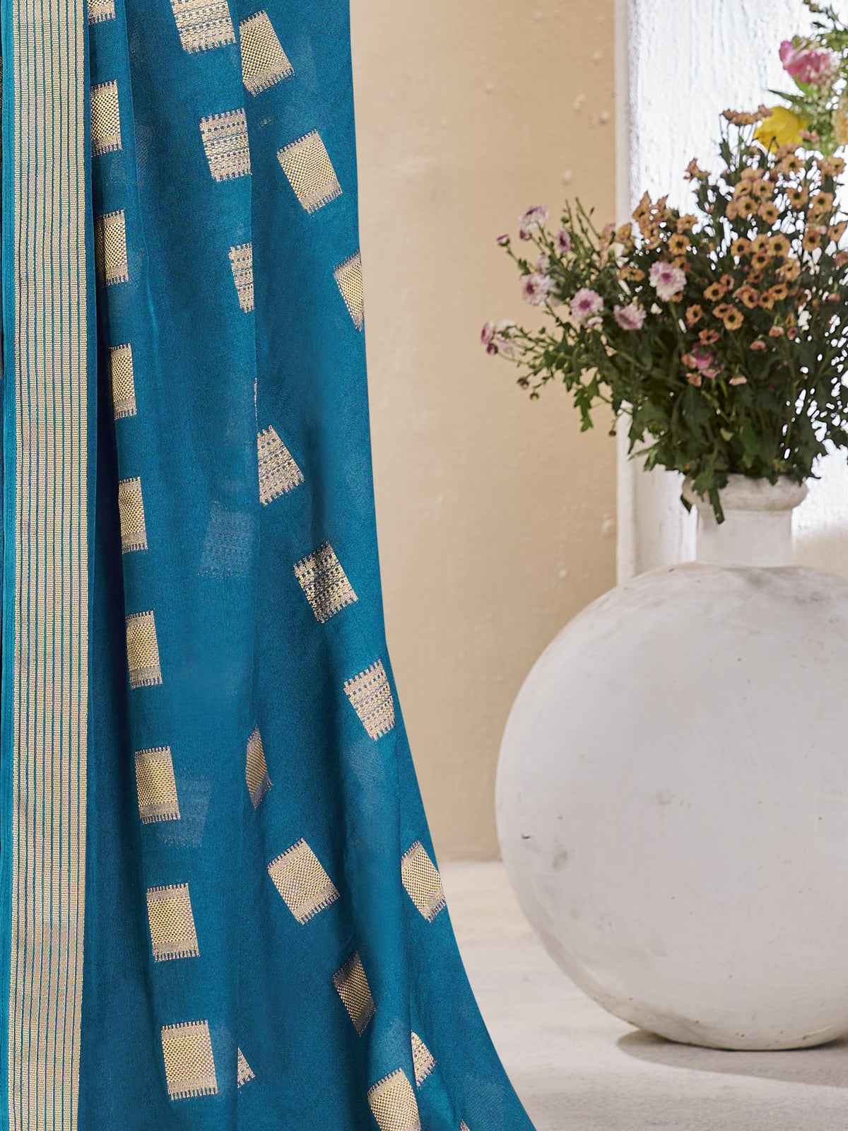 Pallu detail of teal blue georgette saree showing zari butta (metallic motif) work and zari border