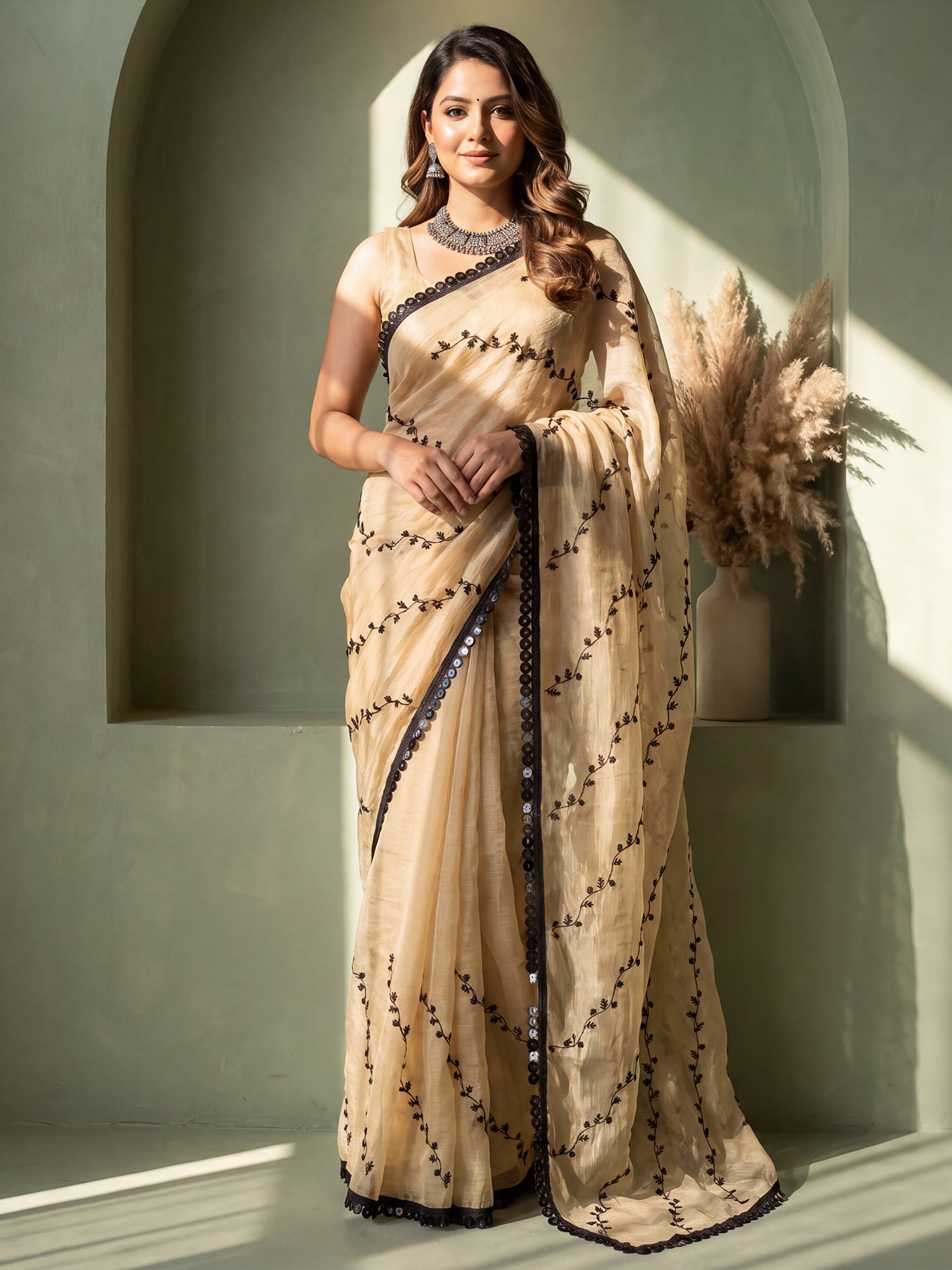 Woman wearing cream chiffon saree with ornamented surface design and cream blouse
