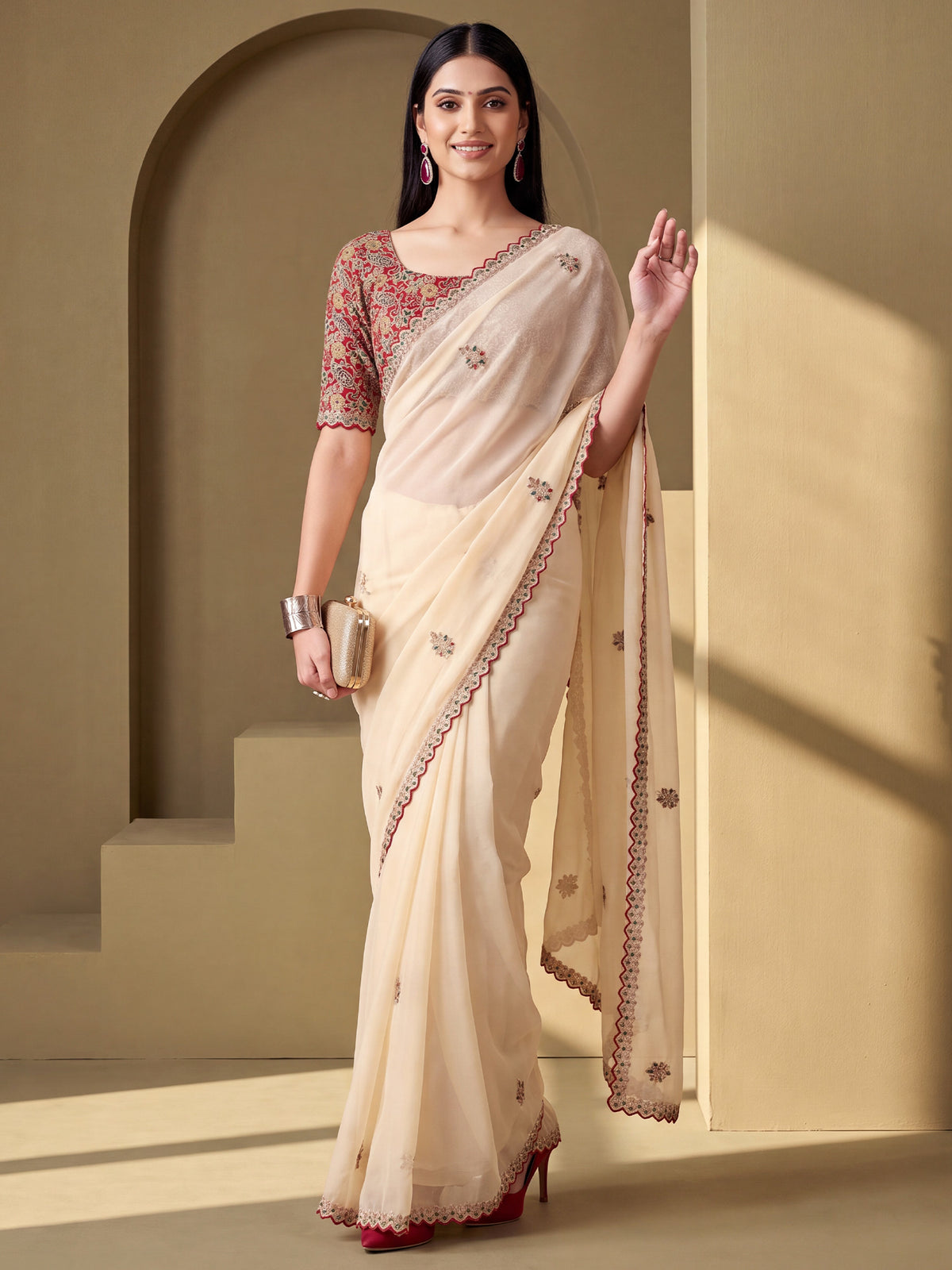 Woman wearing cream tissue saree with ornamented surface design and maroon blouse