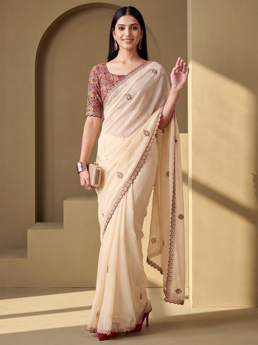 Woman wearing cream tissue saree with ornamented surface design and maroon blouse