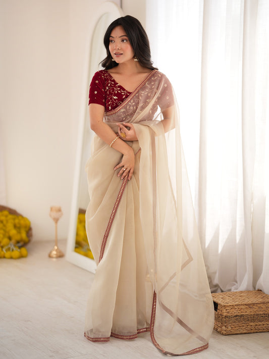 Woman wearing beige net saree with clean solid-tone finish and maroon blouse