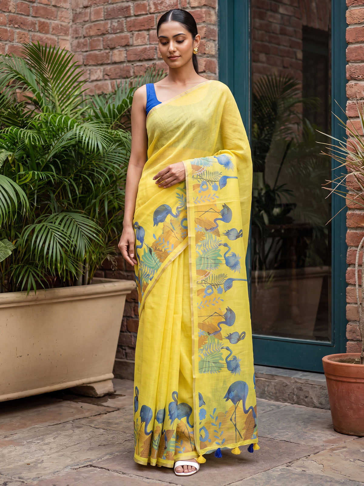 Woman wearing yellow cotton linen saree with traditional indian motif work and blue blouse