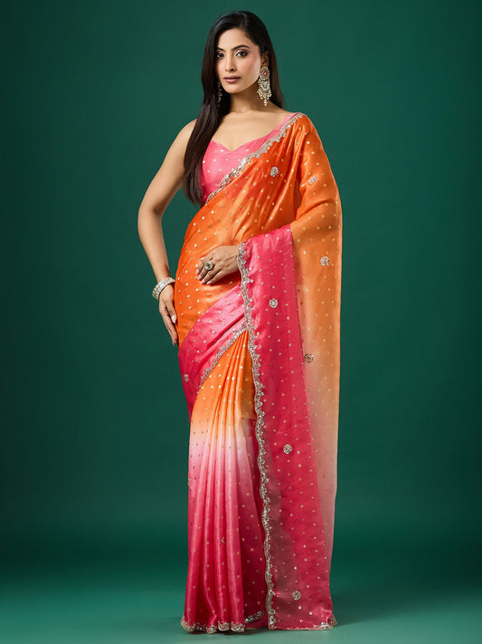 Woman wearing orange satin saree with ornamented surface design and pink blouse
