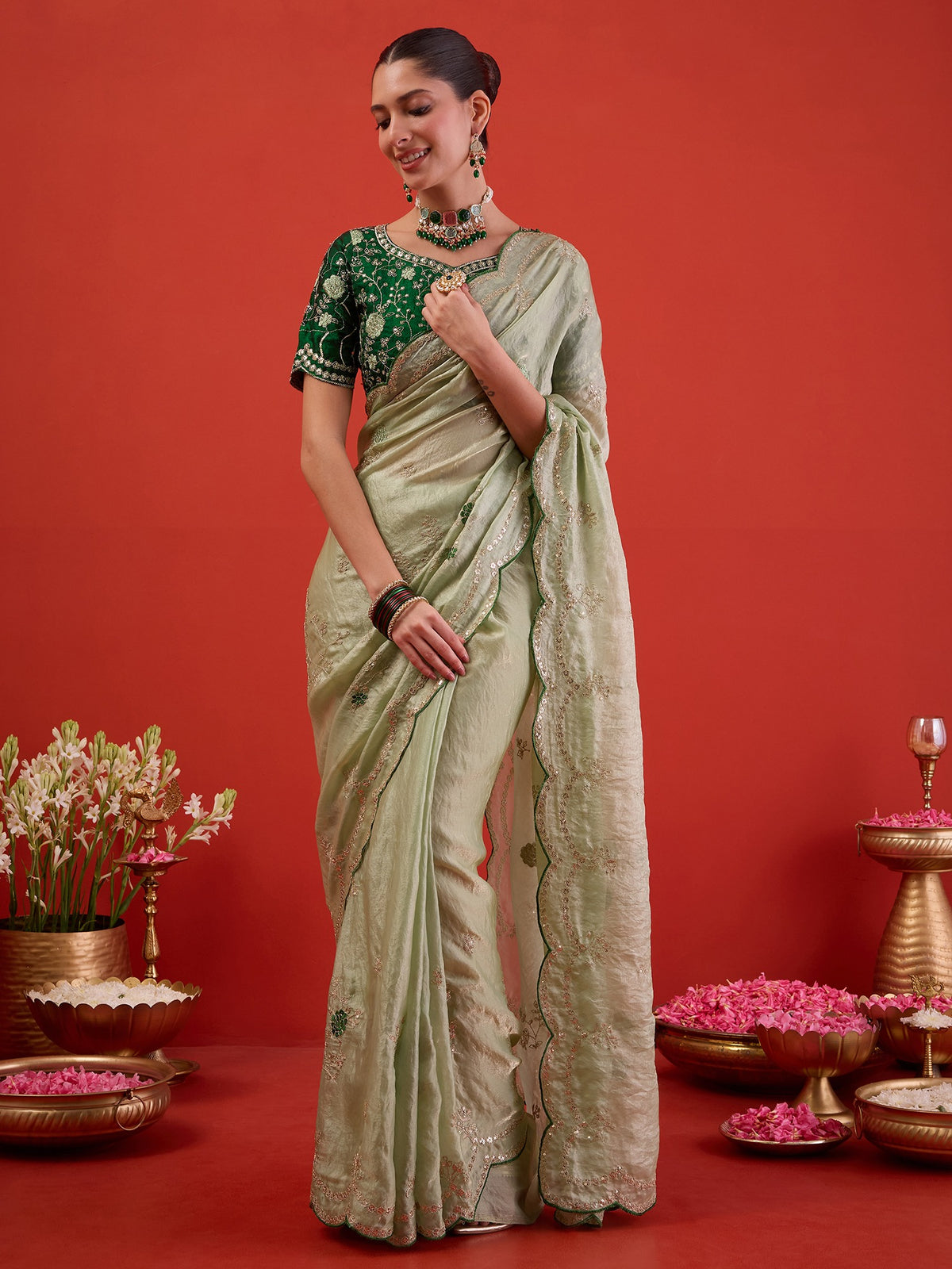 Woman wearing light green satin silk saree with ornamented surface design and dark green blouse