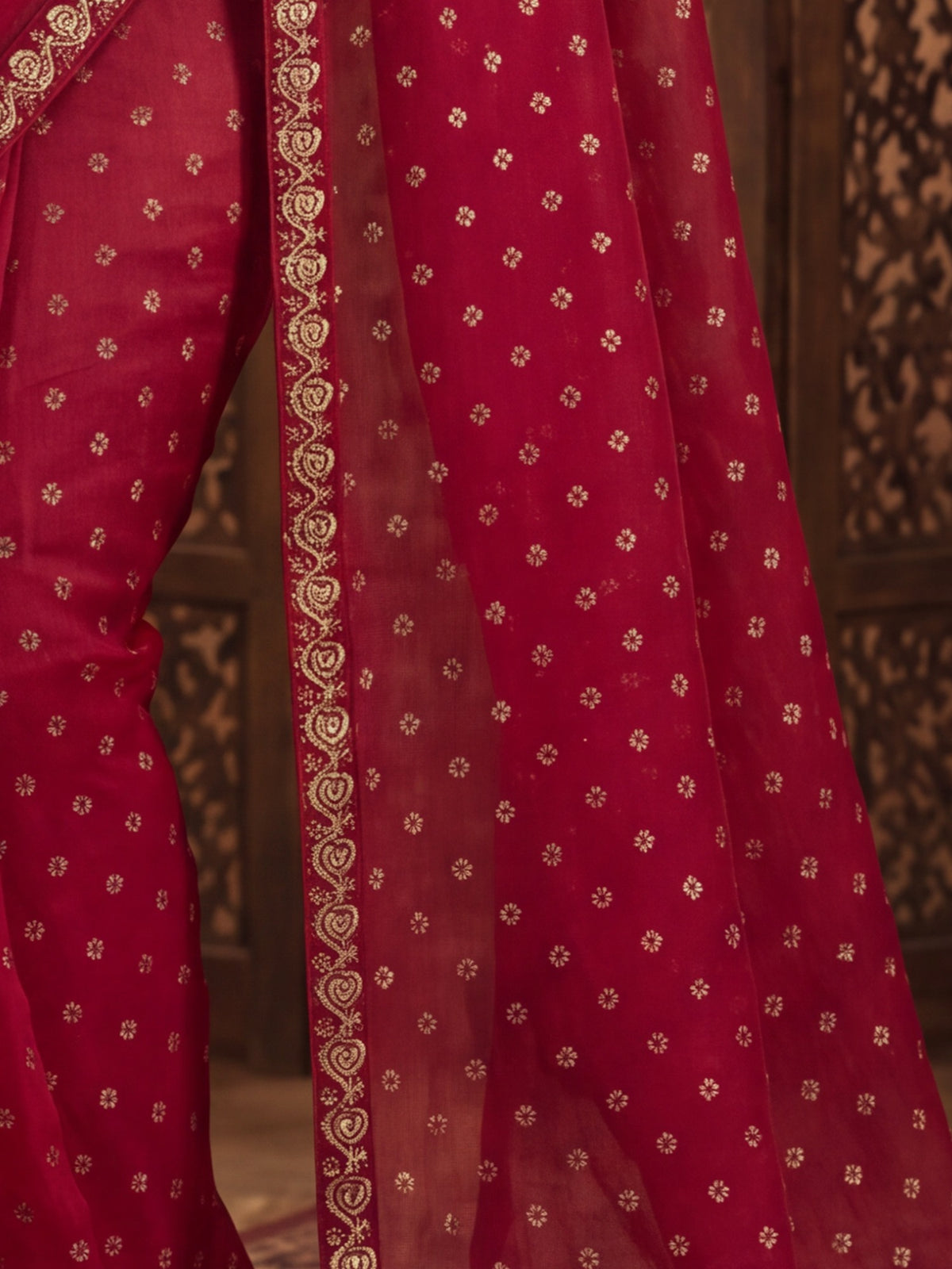 Pallu detail of red chiffon saree showing metallic foil print work and embellished border