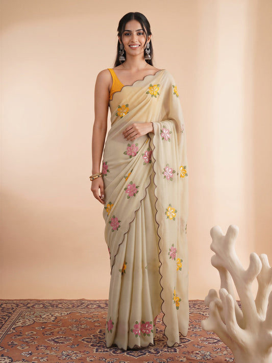 Woman wearing cream georgette saree with embroidered motif work and yellow blouse