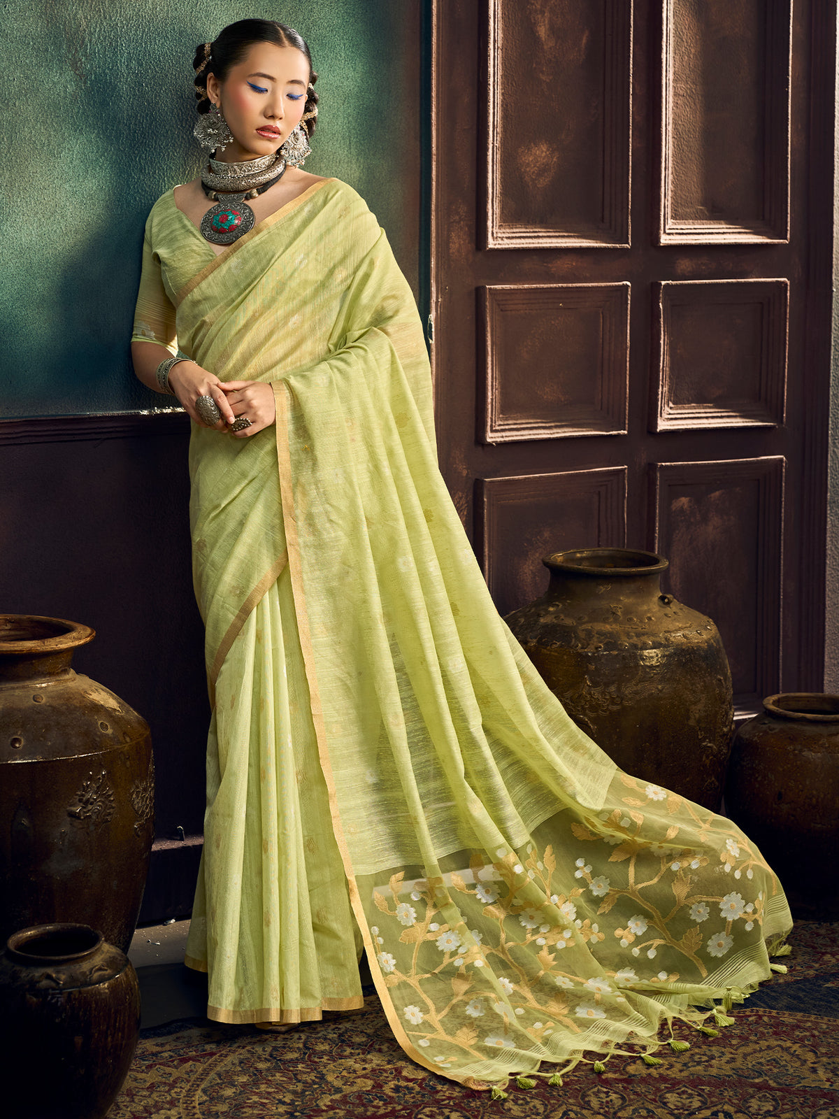 Woman wearing light green muga cotton saree with zari butta (metallic motif) work and light green blouse